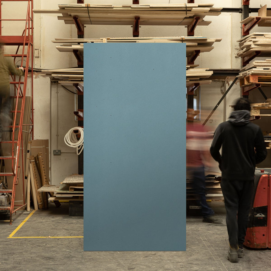 Full sized timber terrazzo sheet standing upright in a workshop setting, the surface is Blue with Oak wood chips